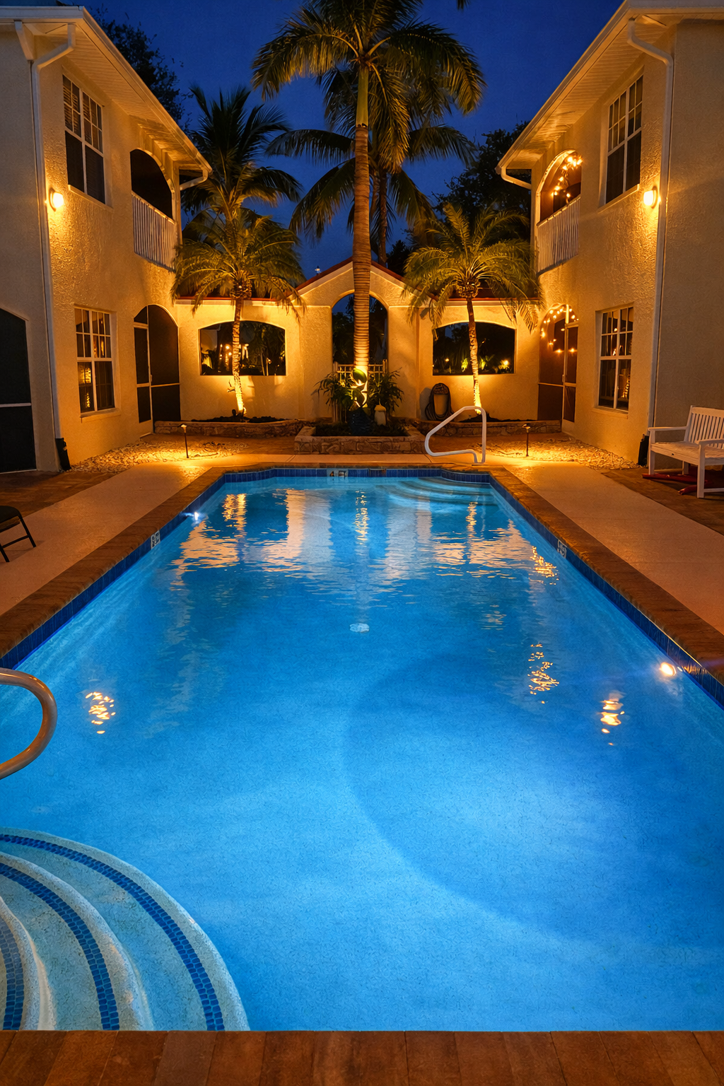 Resort-style pool at night with palm trees and warm lighting